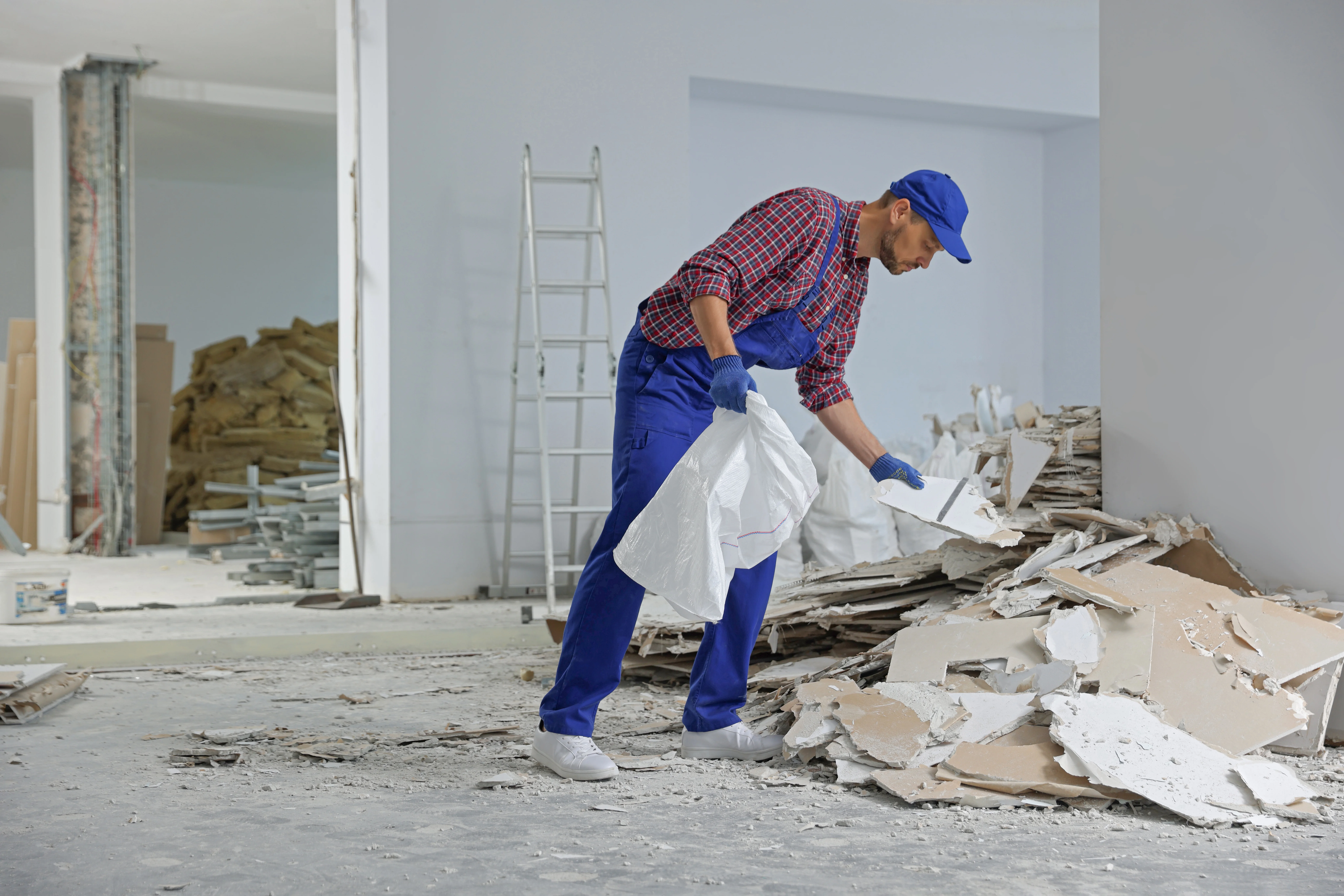 Worker removing construction debris and waste during post construction cleaning